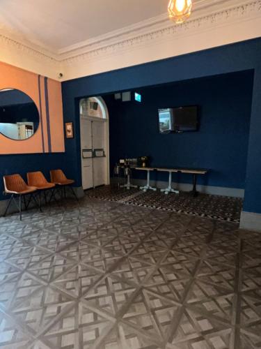 a room with a blue wall with a table and chairs at The Blue Piano Guesthouse in Birmingham