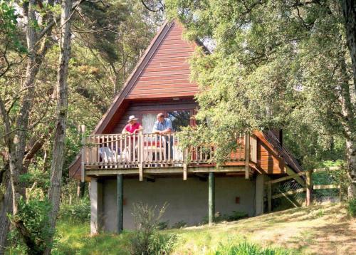 two people standing on a deck of a tree house at Delny Highland Lodges in Invergordon