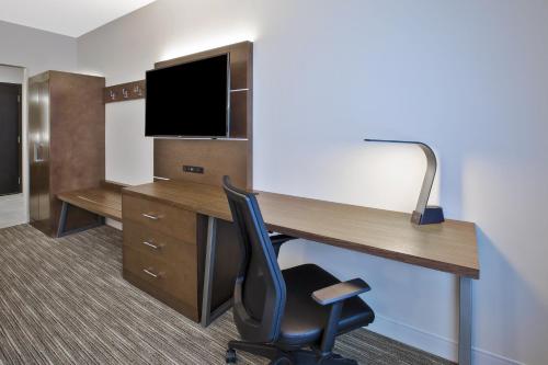 an office with a desk and a chair and a tv at Holiday Inn Express & Suites Okemos - University Area by IHG in Okemos