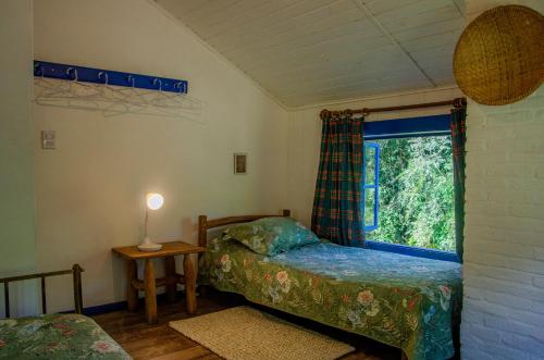 a bedroom with two beds and a window at Hospedaria Fazenda São João do Vale da Grama in Visconde De Maua