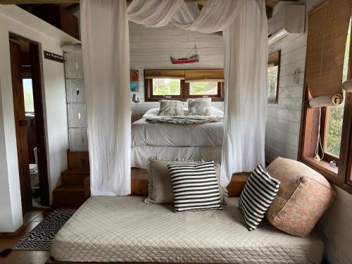 1 dormitorio con 1 cama y 1 sofá con almohadas en Las Chasconas Cabañas Boutique, en Punta del Diablo