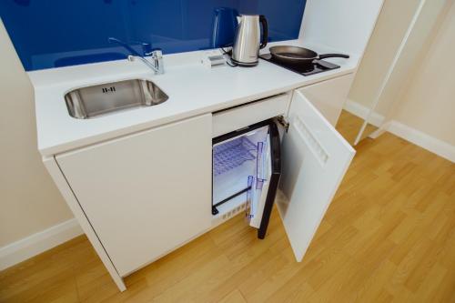 a white kitchen with a sink and a refrigerator at Orbi City Towers in Batumi