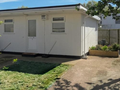 a white house with a door and a yard at Chalet One in West Bay