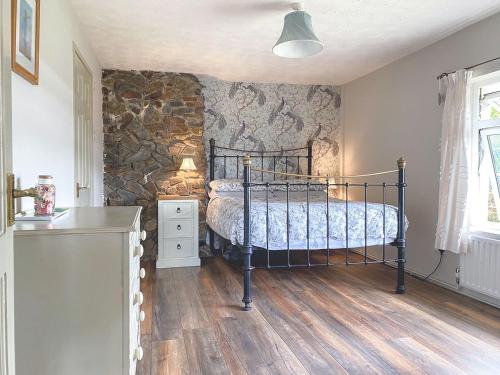 a bedroom with a bed and a stone wall at Holemoor Cottage in Bridgerule
