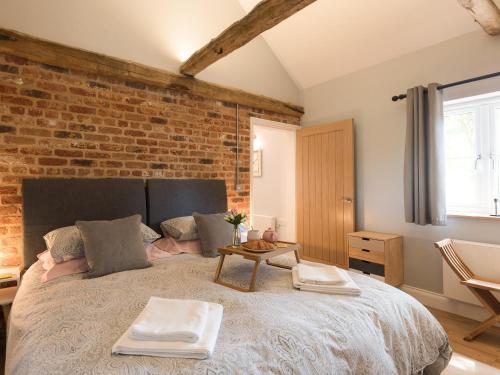 a bedroom with a large bed with a brick wall at Rivers Rest in Brampton