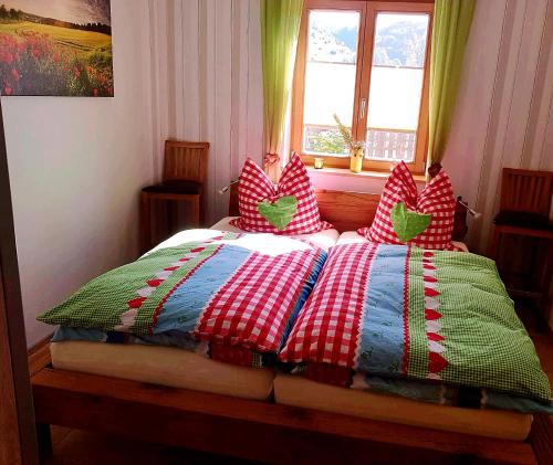 a bed with a red and white quilt and a window at Ferienwohnung NatureOne in Kaltennordheim