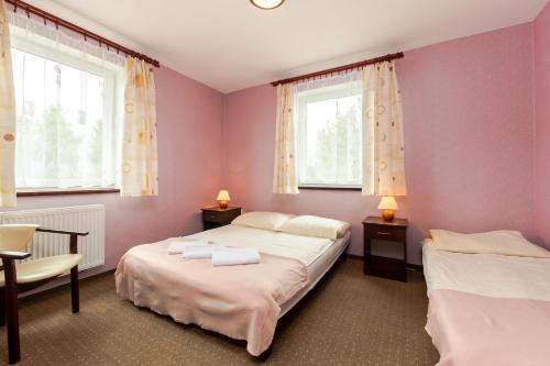 ミエルノにあるVilla Finezja Pokoje Goscinneのピンクの壁と窓が特徴の客室で、ベッド2台が備わります。