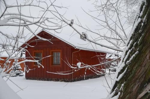 a red cabin in the snow with snow covered branches at Holiday home at Aquapark Tatralandia in Liptovský Mikuláš