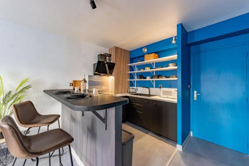 a kitchen with blue walls and a bar with stools at Solstice T2 Hypercentre SmartTV Wifi in Pamiers