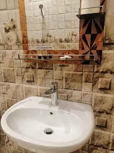 een badkamer met een witte wastafel en een spiegel bij Three Rose in Al Ula