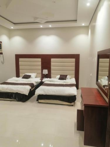 een slaapkamer met twee bedden en een bureau bij Three Rose in Al Ula