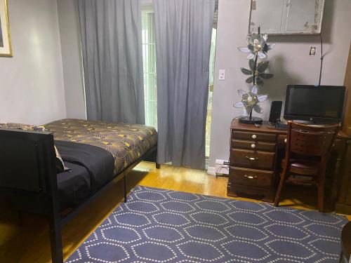een slaapkamer met een bed, een bureau en een televisie bij Double-Mirrored Glass Room in Queens in Corona