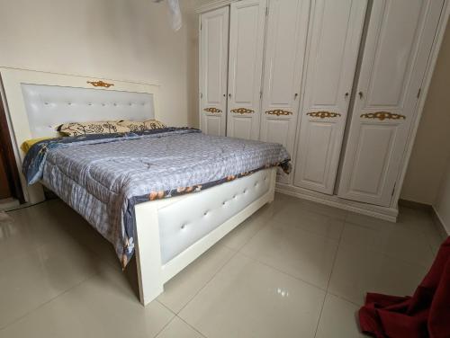 a bedroom with a bed and some white cabinets at Grand Mbao in Mbaw