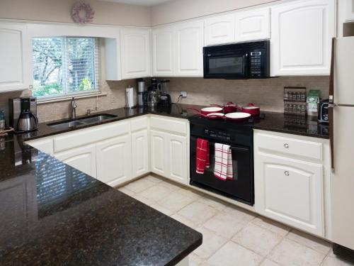 a kitchen with white cabinets and a black appliance at King Bed in Relaxing Oasis, with FREE Snack/Wi-Fi/Parking in San Marcos