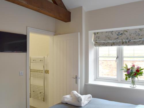 a bedroom with a bed and a window and a vase of flowers at Betley Court Farm 2 in Betley