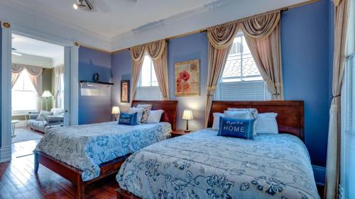 two beds in a room with blue walls and windows at The Jepson Estate on Forsyth Park! in Savannah
