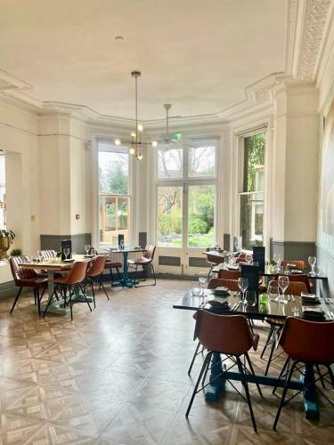 a large room with tables and chairs and windows at The Blue Piano Guesthouse in Birmingham