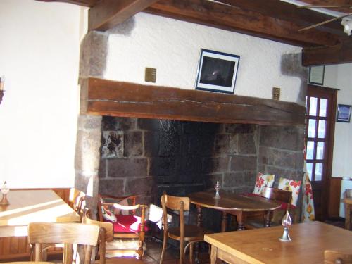 a room with a stone fireplace with a table and chairs at Auberge Hôtel de Tournemire - Cantal in Tournemire
