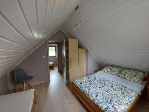 a bedroom with a bed and a chair in a attic at Domek u Beti in Wąglikowice