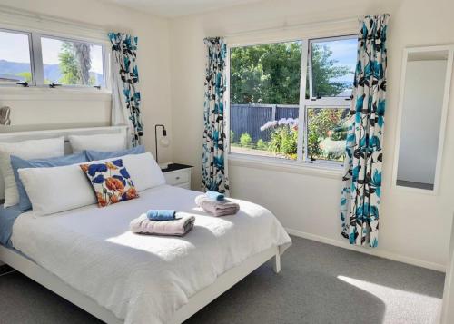 a bedroom with a bed and two windows at Central Garden Guest House in Motueka