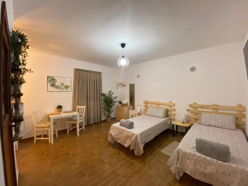 1 Schlafzimmer mit 2 Betten, einem Tisch und Stühlen in der Unterkunft B&B and Apartments El Charco Azul in El Risco