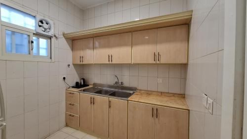 a kitchen with wooden cabinets and a sink at جولدن العرين Golden Al3areen abha hotel in Abha