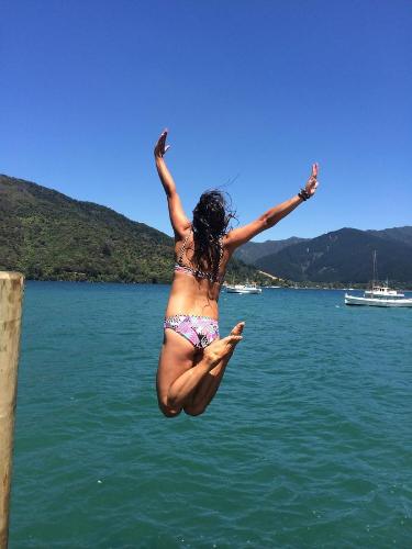 a woman jumping into a body of water at Anakiwa Lodge in Anakiwa