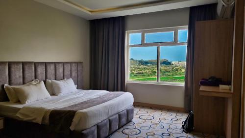 a bedroom with a bed and a large window at جولدن العرين Golden Al3areen abha hotel in Abha