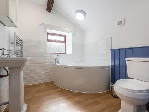 a bathroom with a tub and a toilet and a sink at The Barn House in Hawes