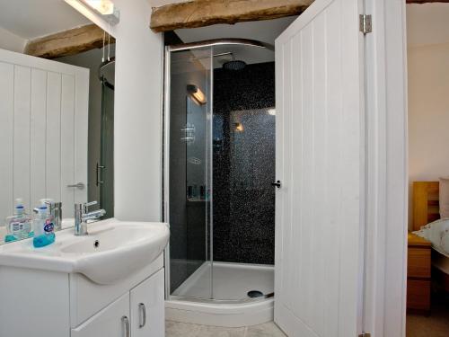 a white bathroom with a shower and a sink at Bluetit Cottage in Kings Nympton