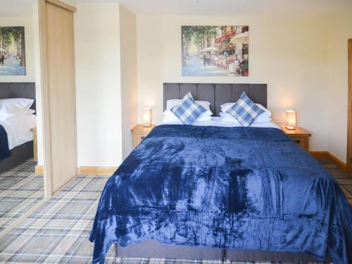 a bedroom with a blue bed with two blue pillows at Uplands in Dalbeattie