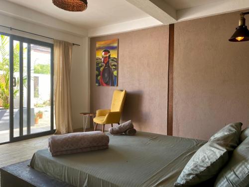 - une chambre avec un lit et une chaise jaune dans l'établissement Casa La Rayanna, à Palomino