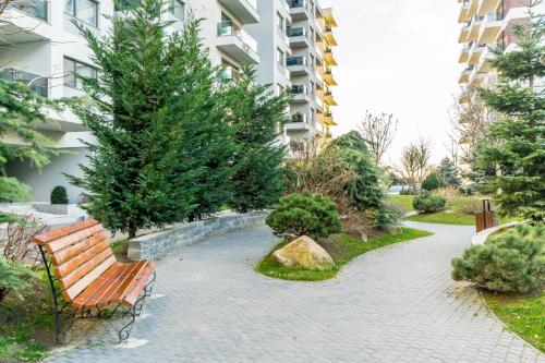 a bench in a park with trees and a building at Luxury Pipera in Voluntari