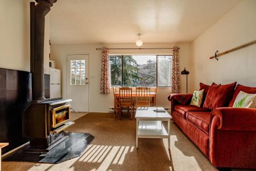 a living room with a red couch and a fireplace at Green Acres Lakeside Resort Salt Spring Island in Ganges