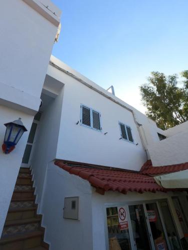 a white building with stairs and a street light at B&B and Apartments El Charco Azul in El Risco