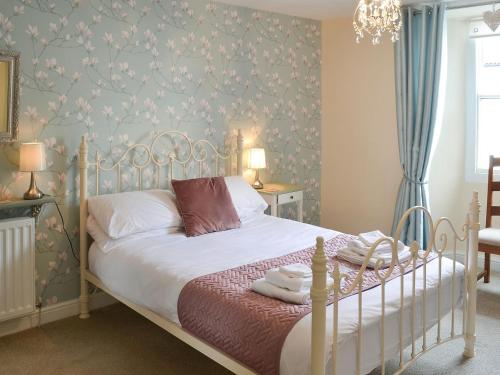 a bedroom with a white bed with floral wallpaper at The Dun Cow in Bishop Middleham