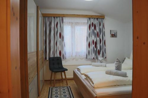 a bedroom with two beds and a chair and a window at Landhaus-Appartements Warraich in Schladming