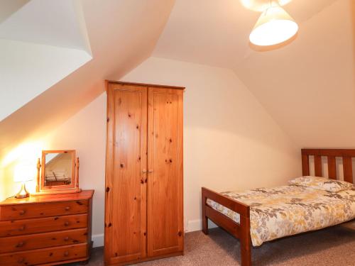a bedroom with a bed and a dresser and a mirror at Craigard in Balmacara
