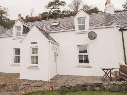 ein weißes Haus mit einem Picknicktisch davor in der Unterkunft Craigard in Balmacara