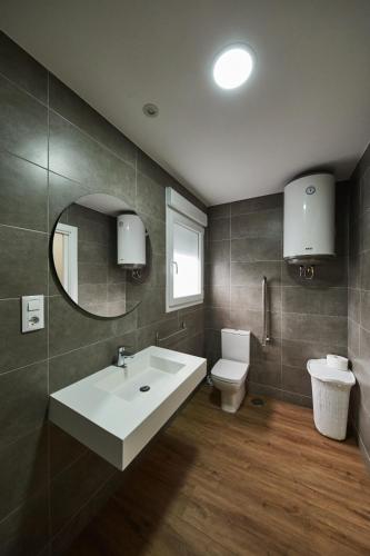 a bathroom with a sink and a toilet and a mirror at A Estreliña in Sigüeiro