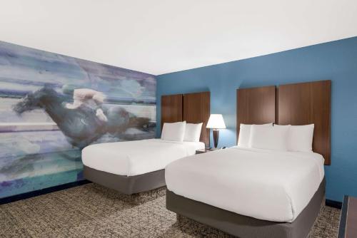 a hotel room with two beds and a painting of a horse at Best Western Winners Circle in Hot Springs