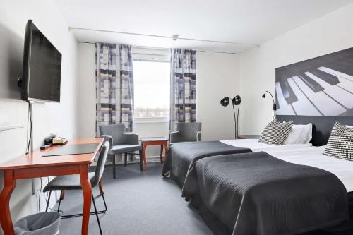 a hotel room with two beds and a desk at Best Western Plus Grand Hotel Elektra in Ludvika