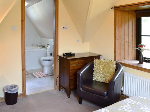 a bathroom with a leather chair and a toilet at Ardlui Church in Ardlui