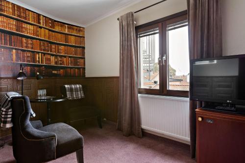 Habitación con biblioteca con silla y TV. en Sure Hotel by Best Western Centralhotellet en Västervik