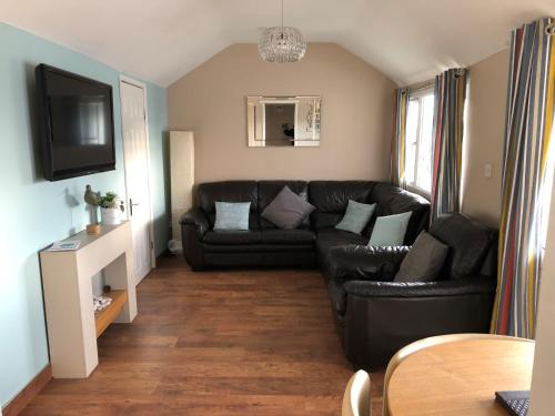 a living room with a black leather couch at Seabirds - 3 bed chalet, dog friendly, Bridlington in Bridlington