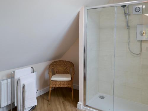 a bathroom with a shower and a chair at High Trees Annex in Widdrington