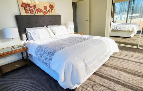 Melbourne Royal Botanical Gardens 2BR في ملبورن: غرفة نوم بسرير ابيض كبير وبلكونة