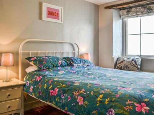 1 dormitorio con 1 cama con edredón de flores en Pollywiggle Cottage, en Keswick