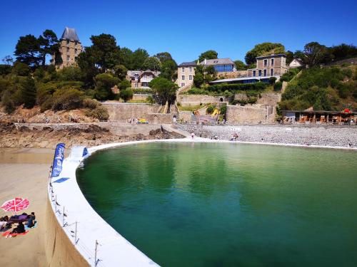 a pool of green water on a beach with buildings at Le colibri in Dinard