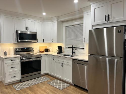 una cucina con armadi bianchi e frigorifero in acciaio inossidabile di City Modern Apartment a Charlottetown